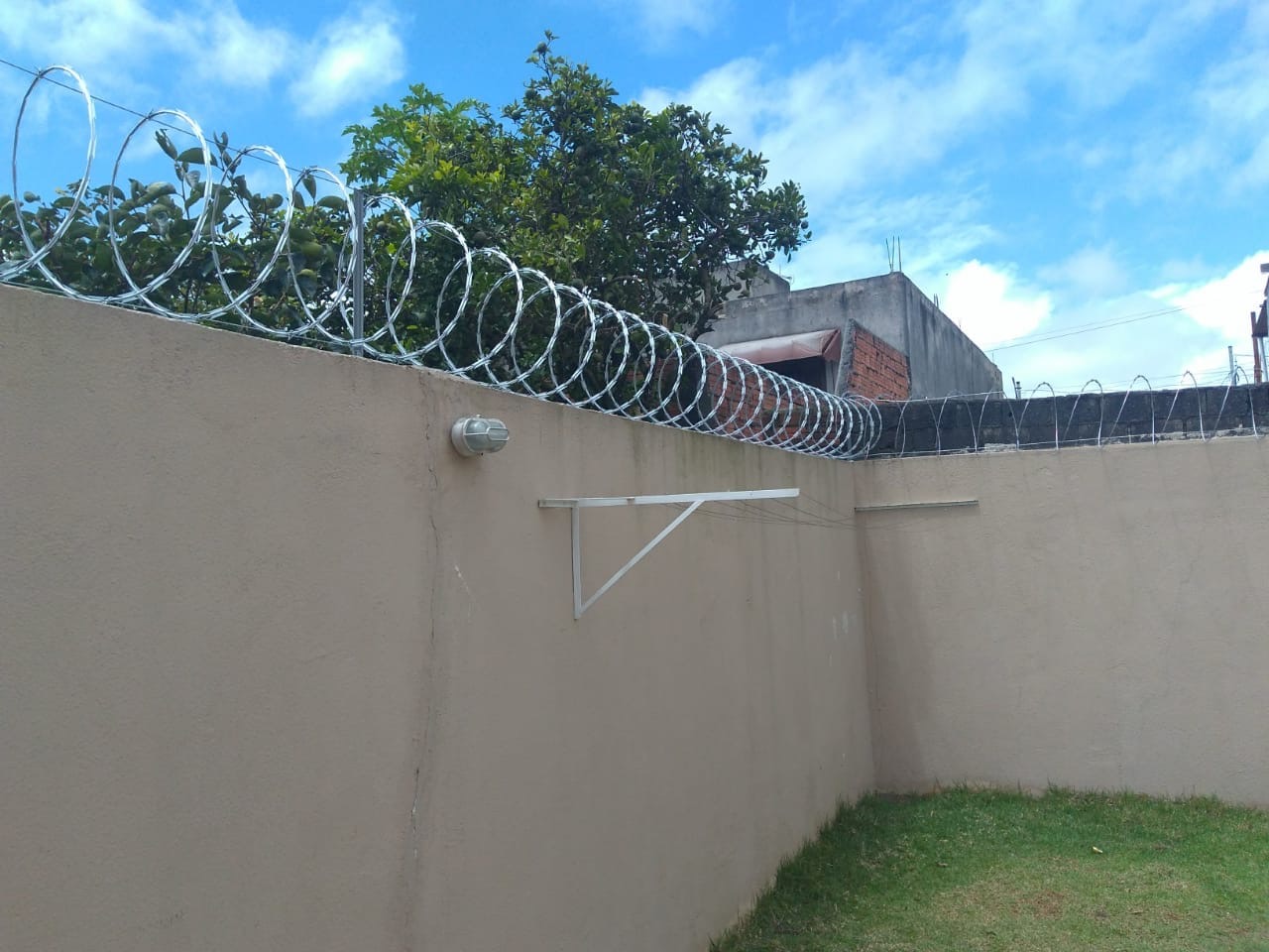 Concertina de aço galvanizado instalada sobre muro de concreto